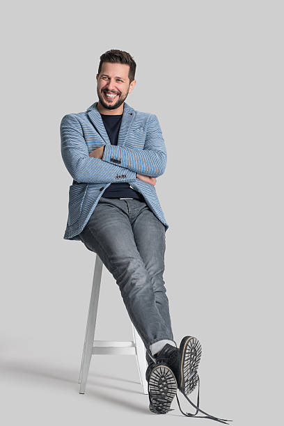 Portrait of handsome man Portrait of handsome man sitting on chair over isolated gray background. Image taken with Sony A7RII camera system and developed from camera RAW. preppy fashion stock pictures, royalty-free photos & images