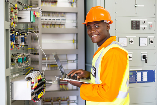 african electrical worker using laptop computer checking transformer