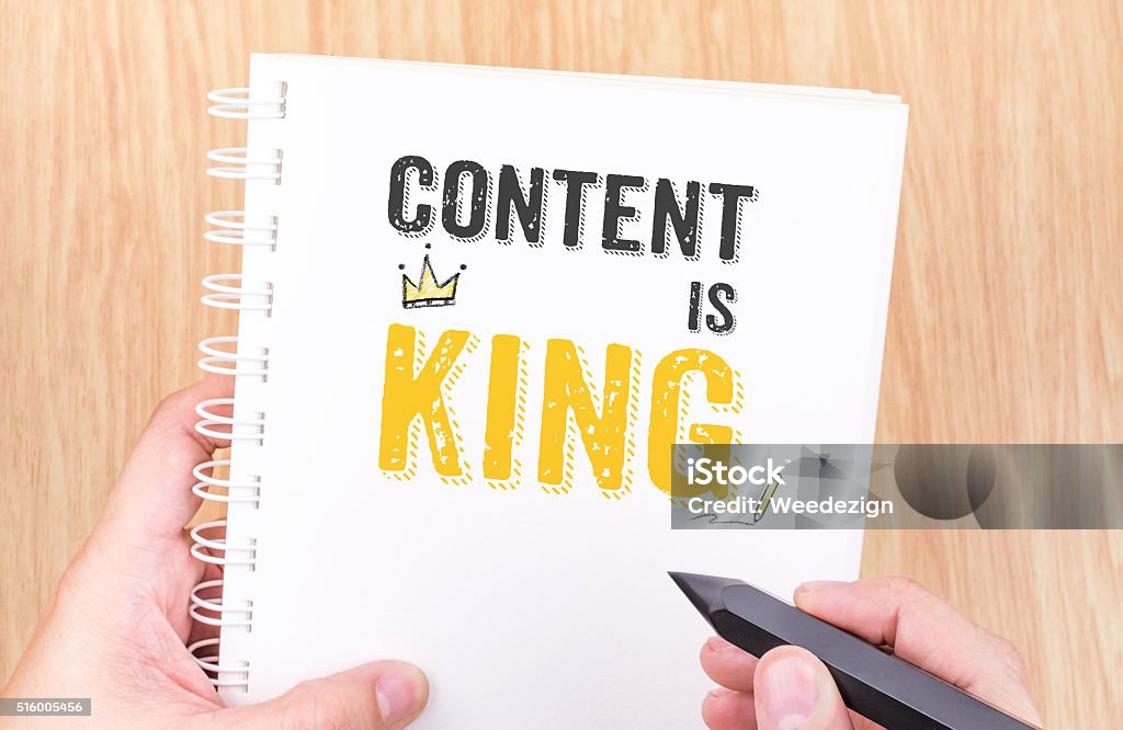Content is King work on white ring binder notebook Content is King work on white ring binder notebook with hand holding pencil on wood table,Digital Business concept. Contented Emotion Stock Photo