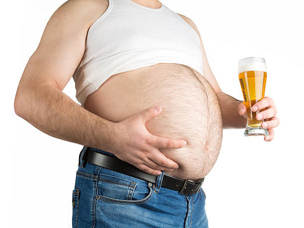 grasso addominale primo piano con birra sola su sfondo bianco - abdomen addiction adult alcohol foto e immagini stock