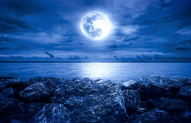 istock Full moon over the ocean with clouds and rocks 516011104