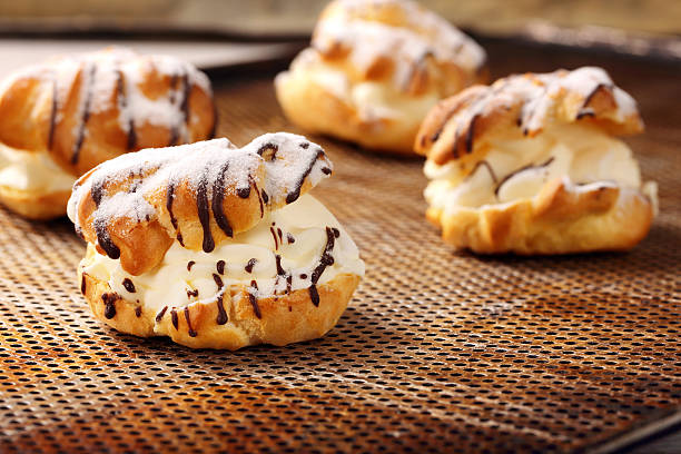 istock Cream puff cake with filling and chocolate icing 516011786