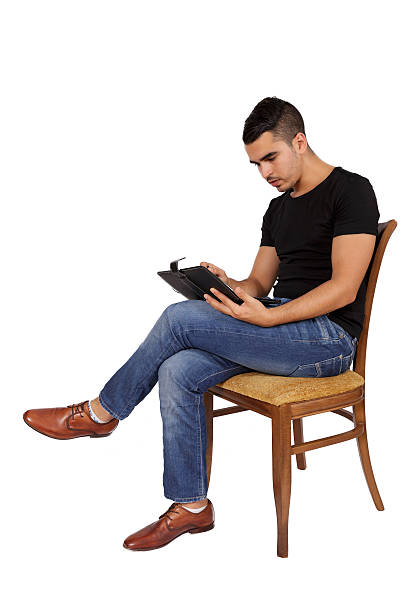 istock young man sitting on a chair looking at a tablet 516014001