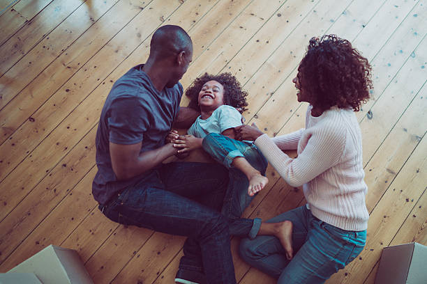 Happy parents tickling son on hardwood floor