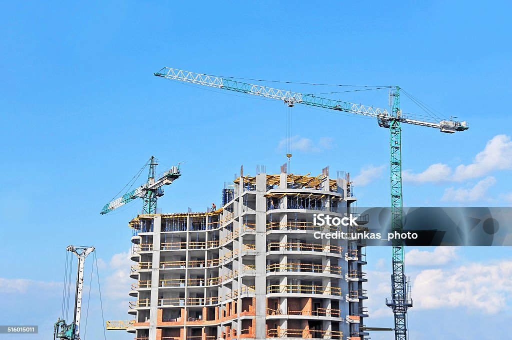 Crane and construction site Crane and building construction site against blue sky Apartment Stock Photo