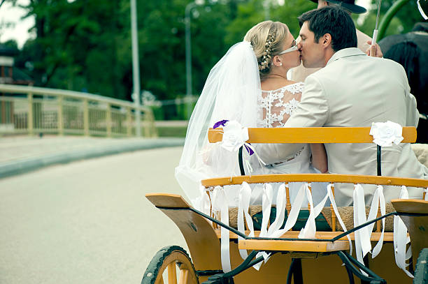 Bride and groom kissing in carriage stock photo