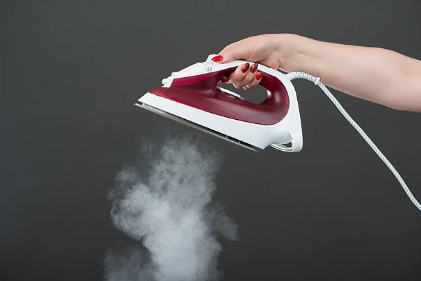 istock Woman holding an iron with steam 516016339