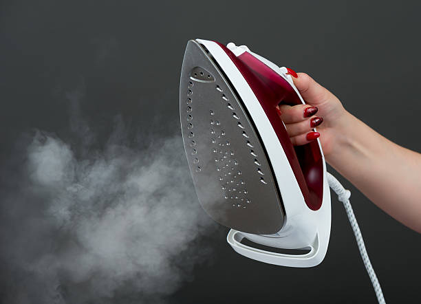 istock Woman holding an iron with steam 516016551