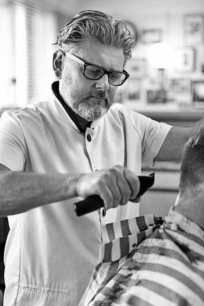 istock Bearded barber trimming hair of a client 516017553