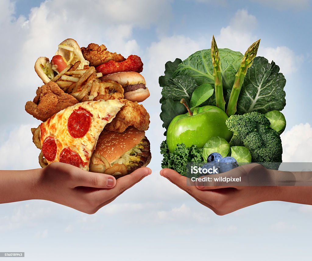 Nutrition Choice Nutrition choice and diet decision concept and eating choices dilemma between healthy good fresh fruit and vegetables or greasy cholesterol rich fast food with two hands holding food trying to decide what to eat. Vegetable Stock Photo