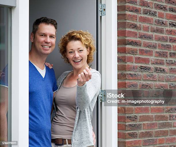 Couple Standing By Door Of New Home Holding Keys Stock Photo - Download Image Now - Front Door, Key, Outdoors
