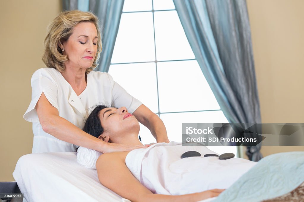 Professional esthetician performing facial and massage treatments for spa customer Spa customer relaxing during facial performed by professional esthetician Adult Stock Photo