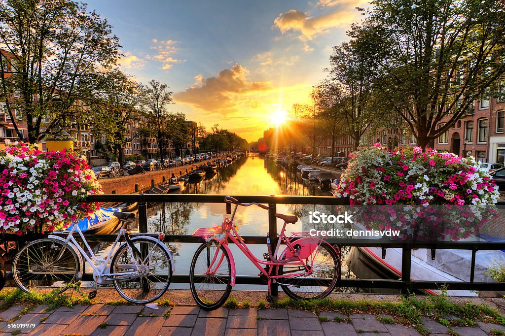 Amsterdam summer sunrise Beautiful sunrise over Amsterdam, The Netherlands, with flowers and bicycles on the bridge in spring Amsterdam Stock Photo