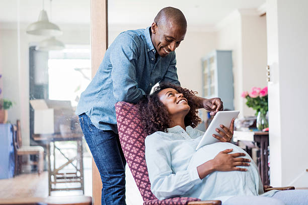 счастливая беременная женщина, глядя на мужчина в домашних - human pregnancy african ethnicity women family стоковые фото и изображения