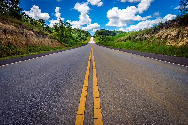 istock Asphalt road through field and clouds on blue sky 516035657