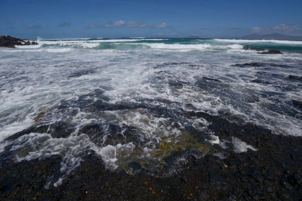 Fuerteventura seascape with volcanic rocks and view of Lanzarote in the background. Taken in Corralejo, Fuerteventura, Canary Islands, Spain.