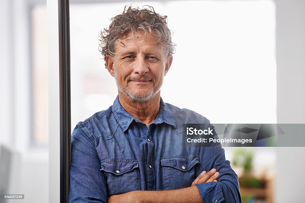 At the top of his game Portrait of a mature businessman standing with his arms folded in an office Doorway Stock Photo