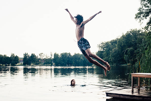 istock carefree summer day: teenagers jumping into a lake 516039061