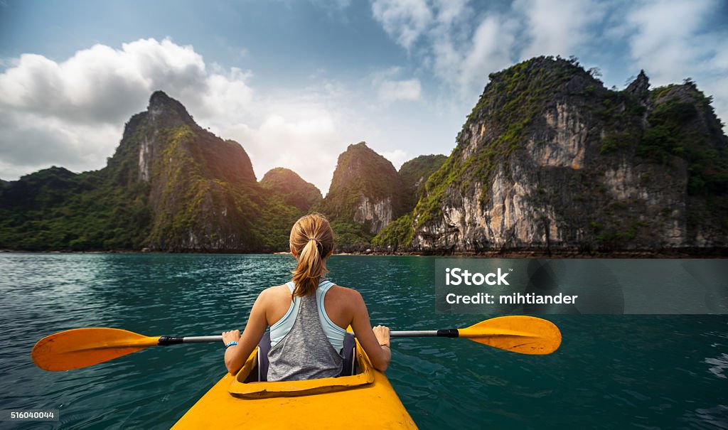 Kayaking Woman exploring calm tropical bay with limestone mountains by kayak. Ha Long Bay, Vietnam Kayaking Stock Photo