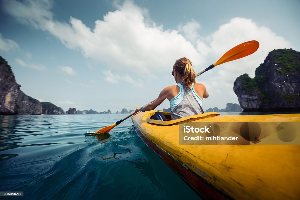 Kayaking Woman exploring calm tropical bay with limestone mountains by kayak. Ha Long Bay, Vietnam Kayaking Stock Photo