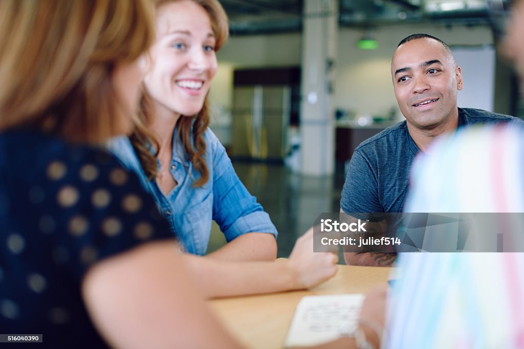 Unposed group of creative business people in an open concept Candid picture of a business team collaborating. Filtered serie with light flares and cool tones. Entrepreneur Stock Photo