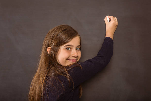 istock Cute pupil writing on chalkboard 516040591