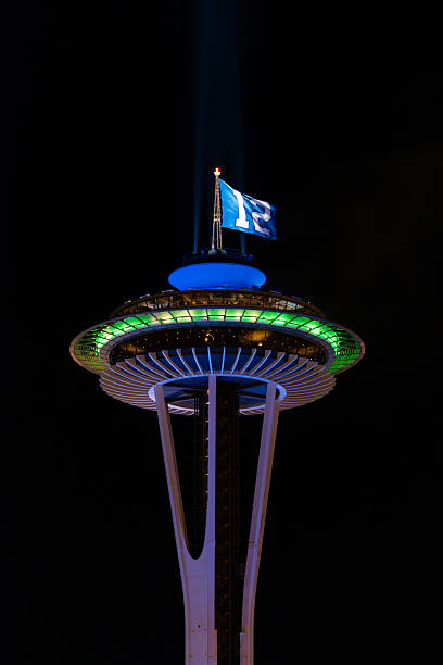 Space Needle Seattle, USA - January 11, 2014: The Seattle Space Needle flying the 12th fan Seahawks flag late into the night. space needle flag stock pictures, royalty-free photos & images