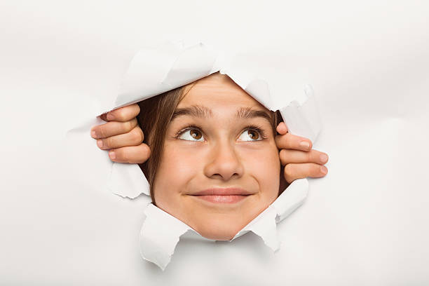istock Cute little girl peeking through paper 516041899