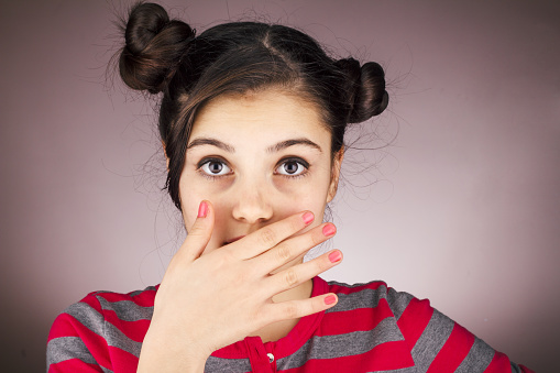 Young girl covering her mouth for halitosis