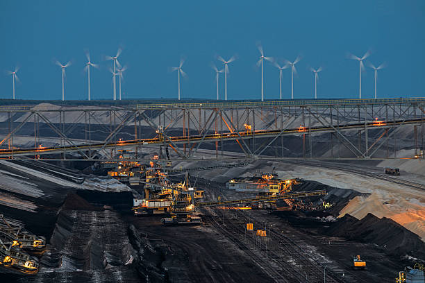 Bucket chain excavators - Lignite mining Lignite mining at dusk. A portion of the overburden conveyor bridge, bucket chain excavators and bucket wheel excavator. In the background, the power plants of the future - wind turbines. Lignite mining Cottbus Nord, Brandenburg, Germany brandenburg state stock pictures, royalty-free photos & images
