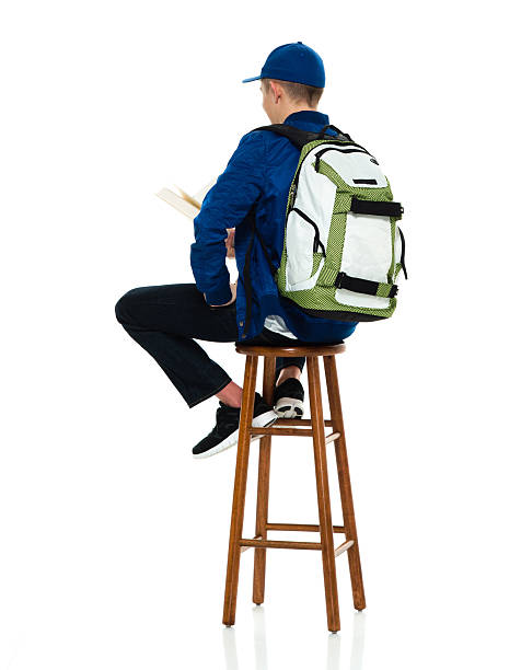 istock Rear view of student sitting and reading book 516044576