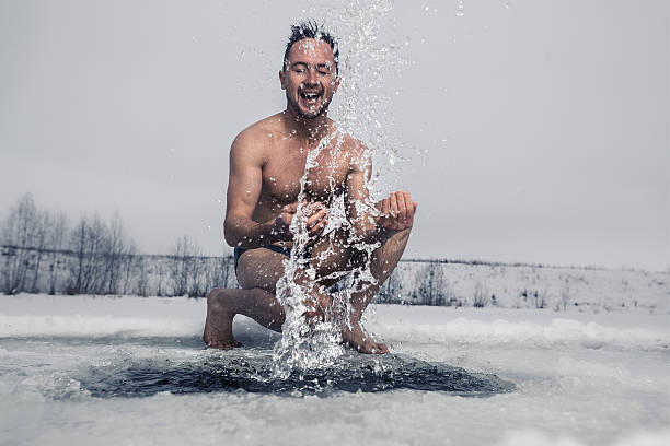 Ice hole fun Young man having fun near the ice hole cold plunge stock pictures, royalty-free photos & images