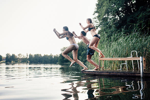 istock carefree summer day: teenagers jumping into a lake 516061057