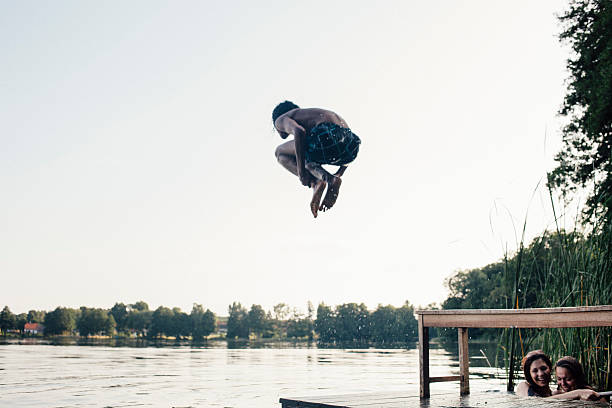 istock carefree summer day: teenager jumps into a lake 516061093