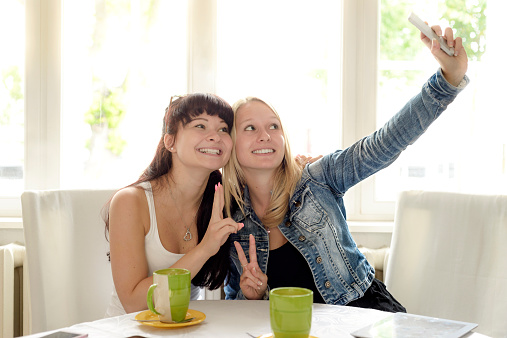 Two young women doing a selfie in a cafe. Brandenburg, Germany