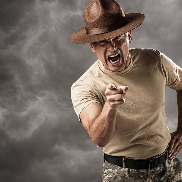 Military Drill Sergeant Barking Orders A mature caucasian male drill sergeant in military uniform points at the viewer and yells commands. barracks photos stock pictures, royalty-free photos & images