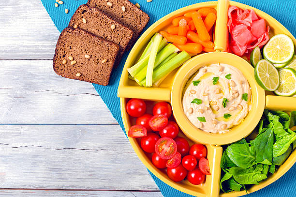 istock hummus, carrots, celery sticks, spinach, ginger, sliced lime, ol 516066254