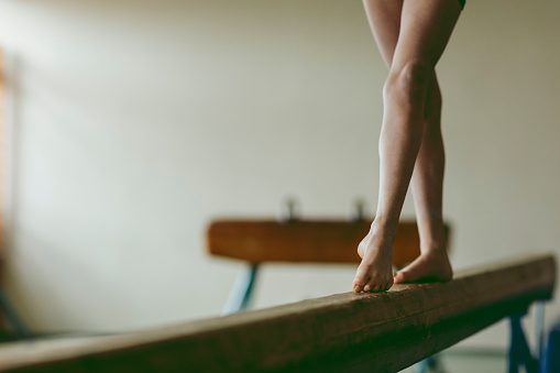 Feet of female gymnast on balance beam, close-up. Low section. Front view.
