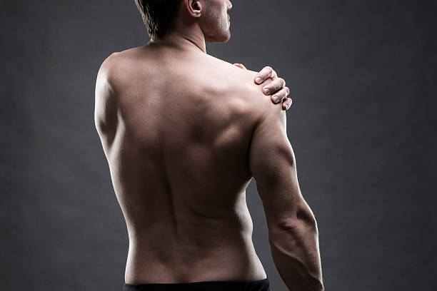 der schulter schmerzen auf grauem hintergrund. - shoulder pain physical injury muscular build stock-fotos und bilder