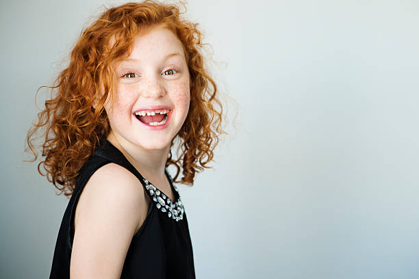 Laughing redhead little girl with freckles and missing tooth. stock photo