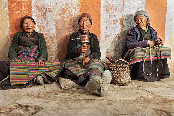три тибетские женщины, молясь в ло manthang, непал - prayer wheel стоковые фото и изображения