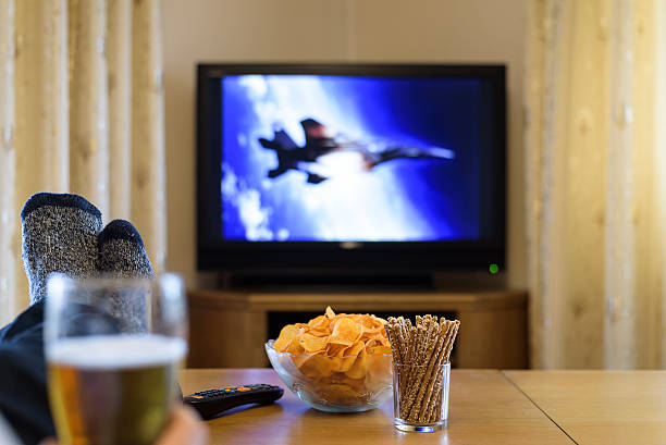istock man watching TV (television) war movie with feet on table 516074326