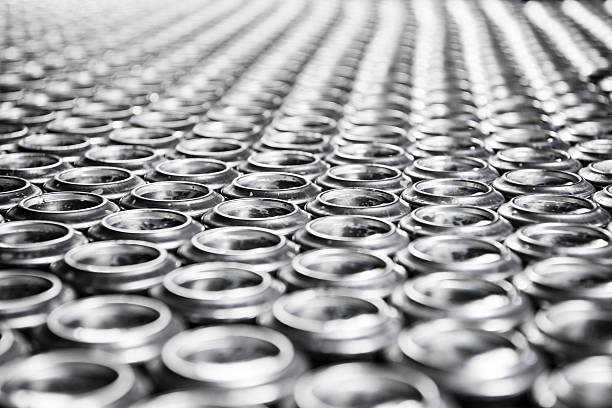 Drinks cans made from aluminium in rows Aluminium drinks cans lined up with focus on foreground and diminishing perspective. Large number of objects, full frame image aluminum plant stock pictures, royalty-free photos & images