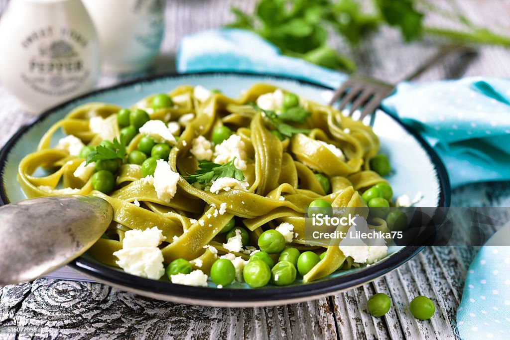 Spinach pasta with green pea and cheese. Spinach pasta with green pea and cheese on old wooden background. Green Pea Stock Photo