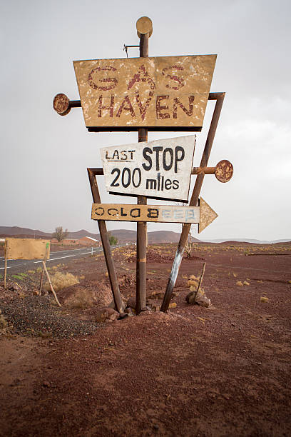 Tall vintage gas sign standing in the desert Tall vintage and abandoned gas sign standing along the deserted road to Ouarzazatein in Morocco. gas station photos stock pictures, royalty-free photos & images