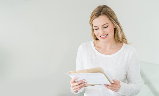 Casual woman at home getting the mail and looking very happy
