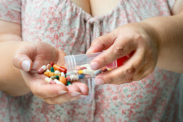 istock Older women pouring medicine into hand. 516081979