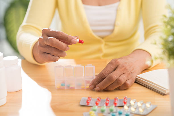 Medication Hands of senior woman putting pills into pill box pill prescription capsule prescription medicine stock pictures, royalty-free photos & images