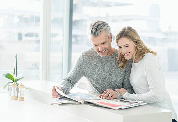 couple looking at the newspaper at home - for rent sign house sign happiness imagens e fotografias de stock