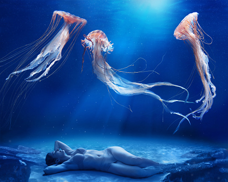 Woman laying on seabed, enjoying jellyfish dance.